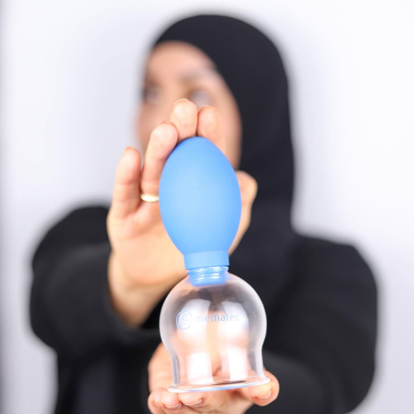 Een glazen cup met een blauwe pompbal, voorgehouden in de praktijk