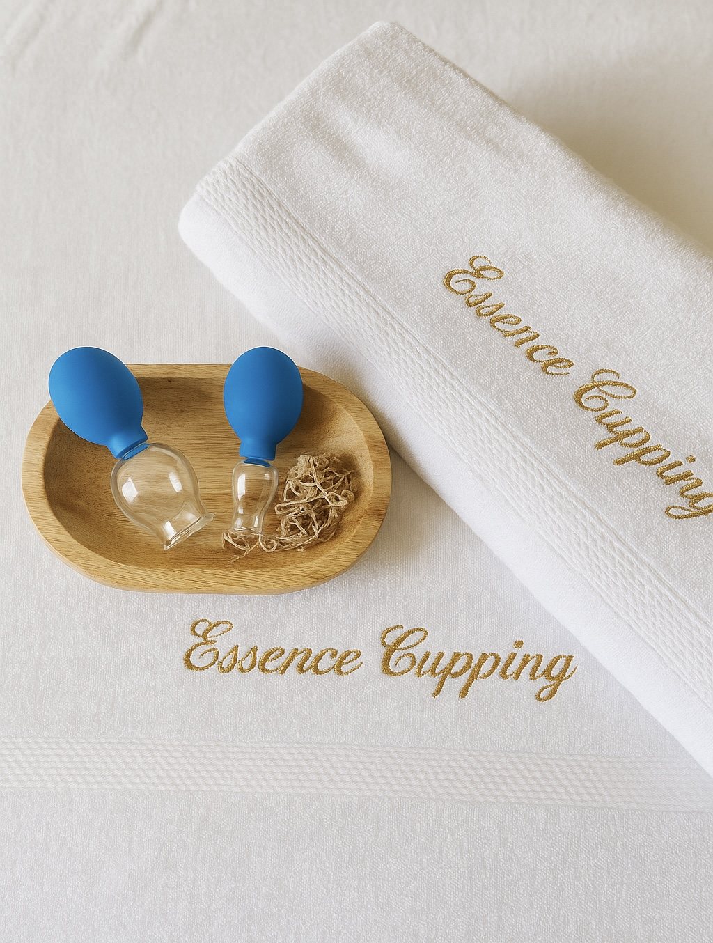 Handdoek met goud geborduurd Essence Cupping en glazen cups op een houten schaal