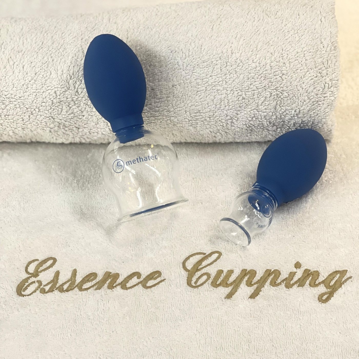 Witte handdoek met het goud geborduurde Essence Cupping en twee glazen cups